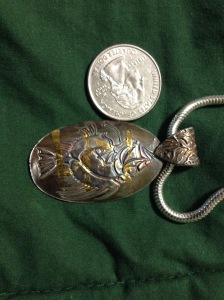 RAN'S KINGDOM. Ran is an old Norse sea goddess. This pendant celebrates her kingdom by combining an image of a fish with fine silver and 22 carat gold. The coin is included to provide scale.